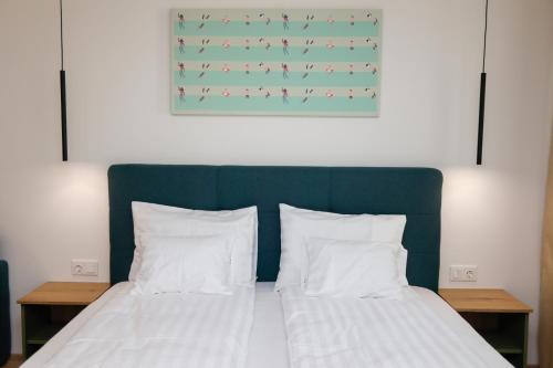 a bed with a green headboard and white sheets and pillows at Várvavár Apartman Gyula in Gyula