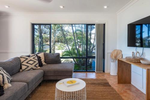 una sala de estar con un sofá y una mesa en Indigo Terrace Two - Oceanstays, en Yamba