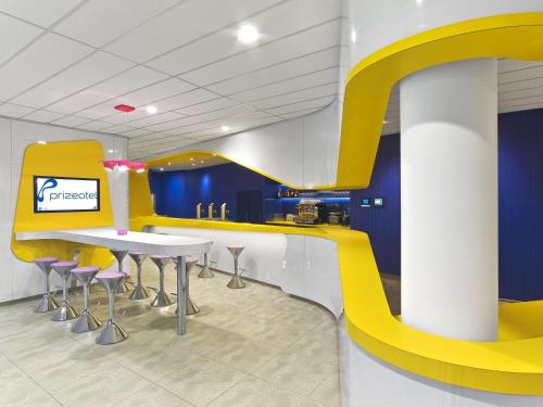 a restaurant with a yellow and white counter and chairs at Prize by Radisson, Hannover City in Hannover