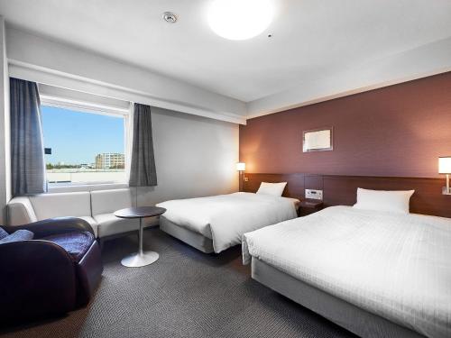 a hotel room with two beds and a window at Daiwa Roynet Hotel Tsukuba in Tsukuba