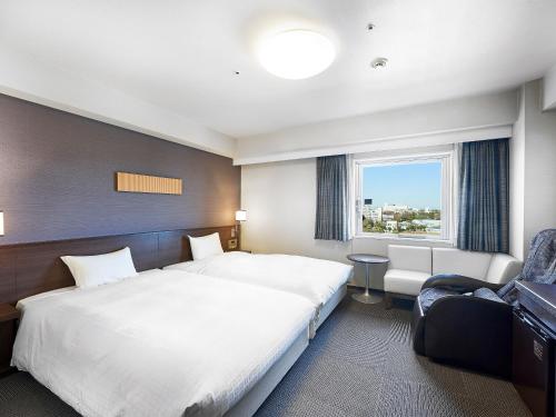 a hotel room with two beds and a window at Daiwa Roynet Hotel Tsukuba in Tsukuba