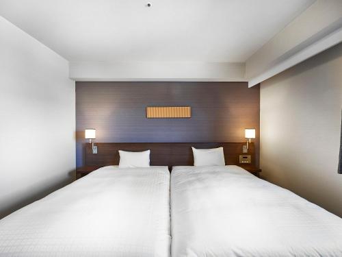 two beds in a room with white sheets at Daiwa Roynet Hotel Tsukuba in Tsukuba