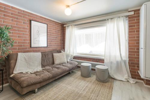 a living room with a couch and a brick wall at BohoSauna in Oulu