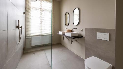 a bathroom with a toilet and a sink and mirror at De Gulden Poorte, a LXRYHOME Hotel Collection in Antwerp
