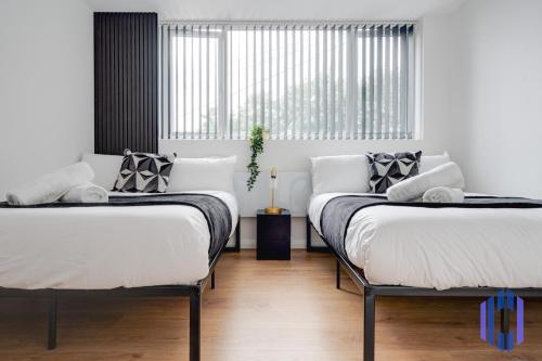 two beds sitting in a room with a window at Sophisticated & Stylish Flat near Manchester Airport - Sleeps 9 in Manchester