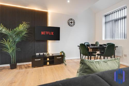 a living room with a table and a tv on a wall at Sophisticated & Stylish Flat near Manchester Airport - Sleeps 9 in Manchester