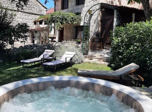 a hot tub in the backyard of a house with chairs at Authentic Stone House Lola in Makarska