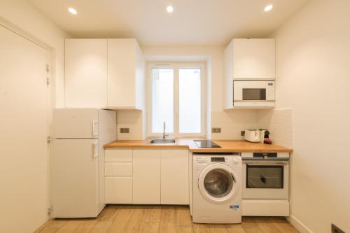 une cuisine avec des armoires blanches et une machine à laver dans l'établissement Cosy apartment 3P - Place de l'Etoile, à Paris