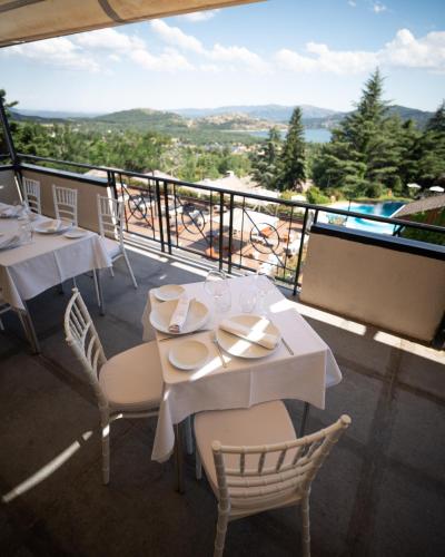 a restaurant with white tables and chairs and a balcony at Hotel Hita "Nature Experience" for all in Navacerrada