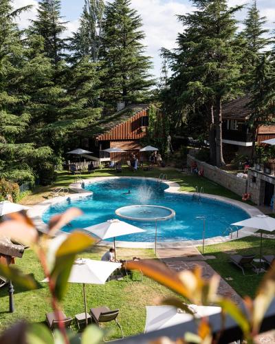 a large blue swimming pool with umbrellas in a yard at Hotel Hita "Nature Experience" for all in Navacerrada
