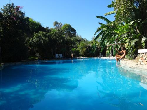 a woman sitting on the edge of a swimming pool at Cabañas DELUXE DUNAS DEL ESTE in Punta Colorada