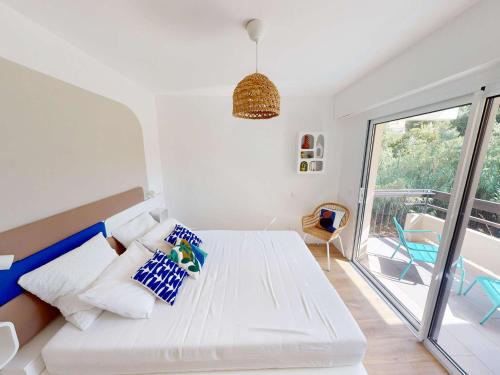 Cette chambre blanche dispose d'un lit et d'un balcon. dans l'établissement Appartement 2 pièces climatisé avec accès direct plage, parking et terrasse - Le Lavandou - FR-1-308-175, au Lavandou
