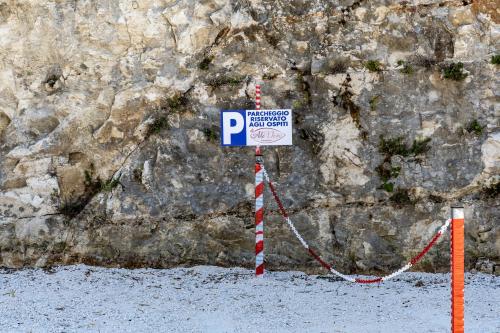 a parking sign in front of a rock wall at Residence AleDen in Vieste