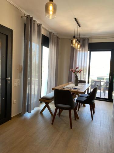 a dining room with a table and chairs and windows at Olia Residences Lesvos in Mytilini