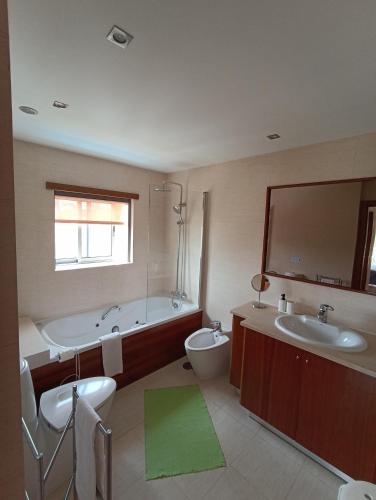 a bathroom with two sinks and a tub and a toilet at Casa do Sol - Entre o Mar e o Pinhal in Apúlia