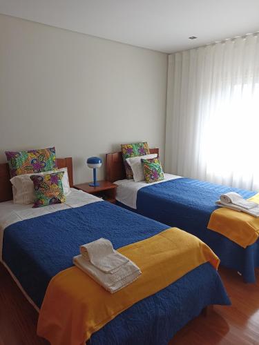 a bedroom with two beds with blue and yellow sheets at Casa do Sol - Entre o Mar e o Pinhal in Apúlia