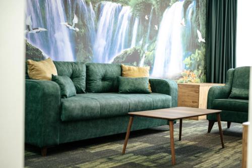 a green couch in a living room with a waterfall mural at M&N Holiday Resort in Ulcinj