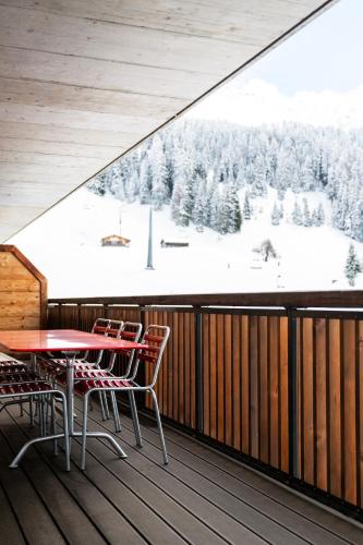 a balcony with a table and chairs and a snow covered mountain at Am Heimberg Skilift - Mullers x Kandahar Suite in Parpan