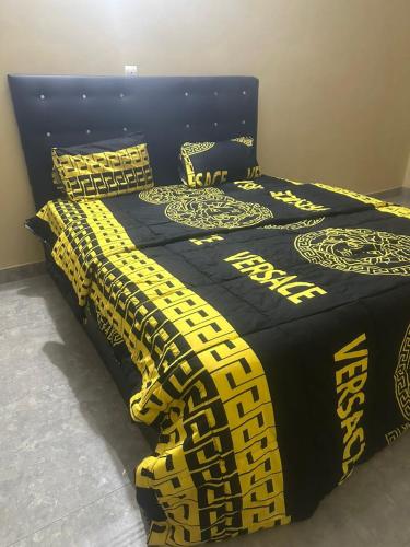 a bed with a black and yellow comforter and pillows at Avina lux homes Spacious one bedroom in Lomé