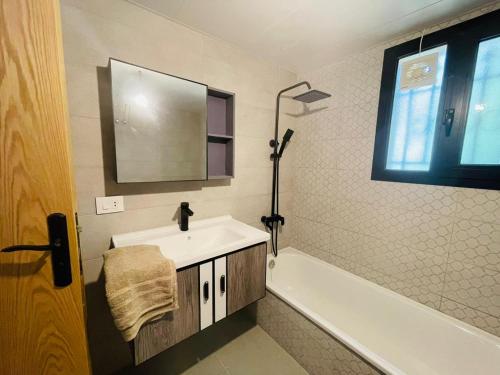 ein Badezimmer mit Waschbecken, Badewanne und Spiegel in der Unterkunft Eleven 11 in Baabda