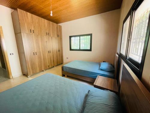 1 Schlafzimmer mit 2 Betten, Holzschränken und einem Fenster in der Unterkunft Eleven 11 in Baabda
