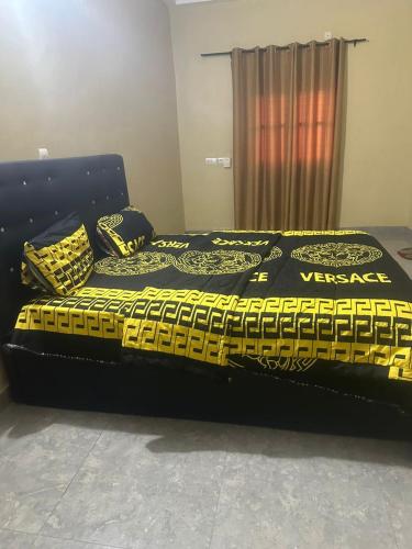a black bed with a yellow and black comforter at Avina lux homes Spacious one bedroom in Lomé