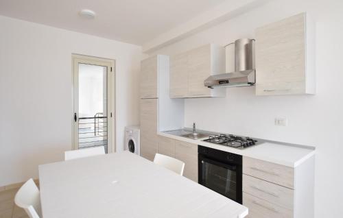 Awesome Apartment In Isca Marina في بادولاتو: مطبخ أبيض مع طاولة بيضاء وموقد