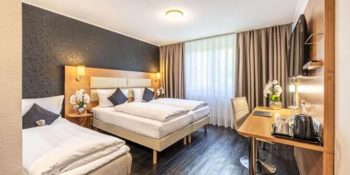 a hotel room with two beds and a desk at PLAZA INN Stuttgart Airport Messe in Filderstadt