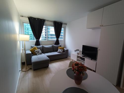 un salon avec un canapé et une télévision dans l'établissement Cozy Studio Heart of La Défense - 10 min to Paris, à Courbevoie