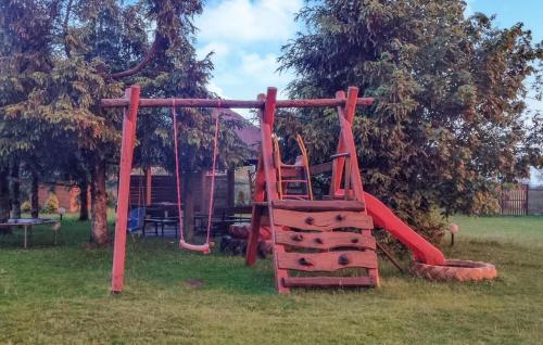 a playground with a red slide in the grass at 1 Bedroom Pet Friendly Home In Rekowo in Rekowo