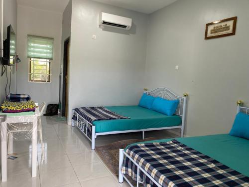 una habitación con dos camas y una mesa en Al Bayt Roomstay Kaki Gunung Jerai, en Kampung Gurun