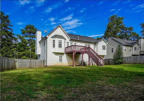 a large white house with a red staircase in the yard at Lovely 5 Bedrooms, 3 Full Baths Home Near Parks! in Austell