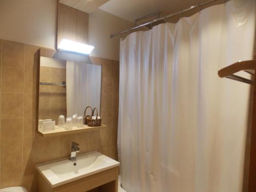 La salle de bains est pourvue d'un rideau de douche blanc et d'un lavabo. dans l'établissement Edelweiss, à Samoëns