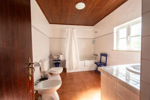 a bathroom with two toilets and a sink and a tub at Quinta do lagar in Chamusca