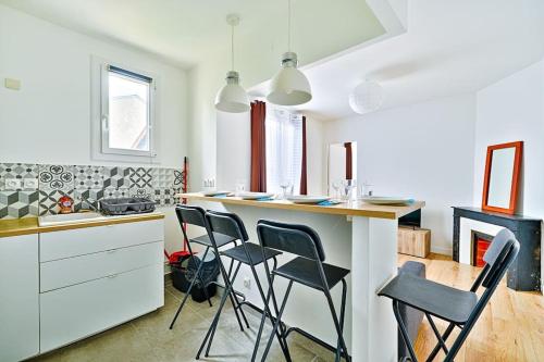 une cuisine avec des chaises noires et un comptoir avec une cuisinière dans l'établissement Welcome to Linda House, à Saint-Maur-des-Fossés