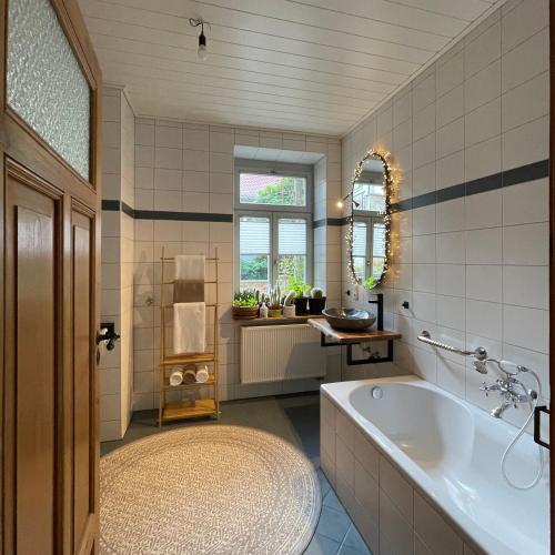 a bathroom with a tub and a sink and a mirror at Feinzeit Cozy Rosy - 1-2 Schlafzimmer, 4-6 Gäste, Parkplatz in Bamberg