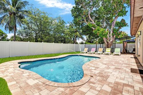 einen Pool in einem Garten mit Stühlen und einem Zaun in der Unterkunft Luxury 4BR & 4BA Villa Heated Pool Minutes To Beach in Hollywood