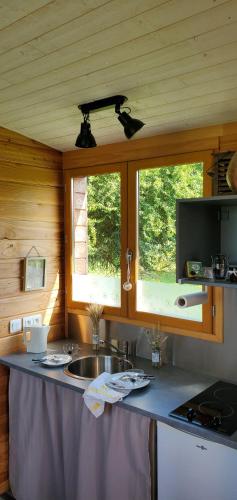 - une cuisine avec un plan de travail, un évier et 2 fenêtres dans l'établissement Roulotte de la Ferme Les Chenevières, à Villers-devant-Mouzon