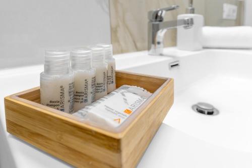 a wooden tray with bottles of milk on a bathroom counter at MI CASA - Appartamento in Ponte Nuovo in Milan