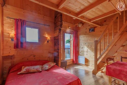 - une chambre avec un lit rouge dans une cabane en rondins dans l'établissement Le megevan-dans les alpages, à La Giettaz