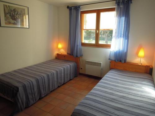 une chambre avec deux lits et une fenêtre avec des rideaux bleus dans l'établissement L' erable aux esperifes, à Vidauban