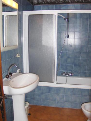 une salle de bain carrelée bleue avec un lavabo et une douche dans l'établissement Gite sur les collines de mandelieu, à Tanneron