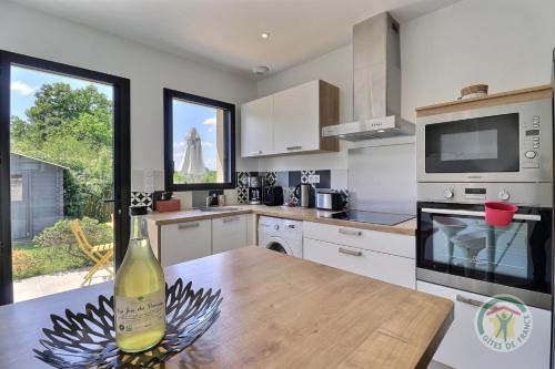 - une cuisine avec une bouteille de vin sur une table en bois dans l'établissement Les blanchets, à Fouillard