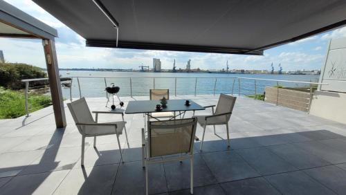 une table et des chaises sur un balcon avec vue sur l'eau dans l'établissement Les minahouets, à Locmiquélic