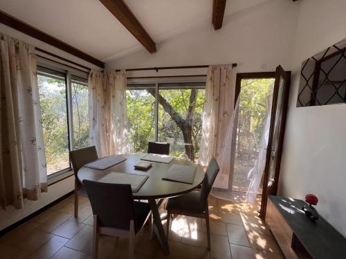 a dining room with a table and chairs and windows at Le gite les bancaous in Solliès-Pont