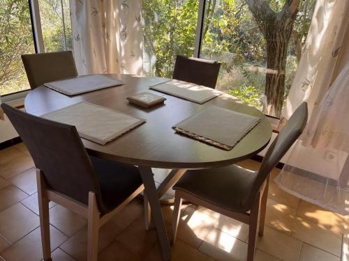a dining room table with chairs and a large window at Le gite les bancaous in Solliès-Pont