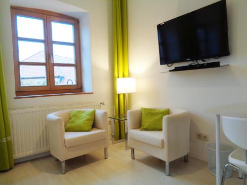 a living room with two chairs and a flat screen tv at Hotel Apartment Puell in Eimersleben