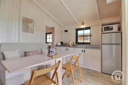 une cuisine avec une table et des chaises dans une pièce dans l'établissement Lodge de l'etang, à Mézières-sur-Couesnon