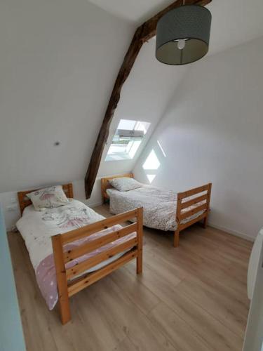 - une chambre mansardée avec 2 lits et une fenêtre dans l'établissement Grande maison de famille - Le Petit Pontébart, à Paimpol