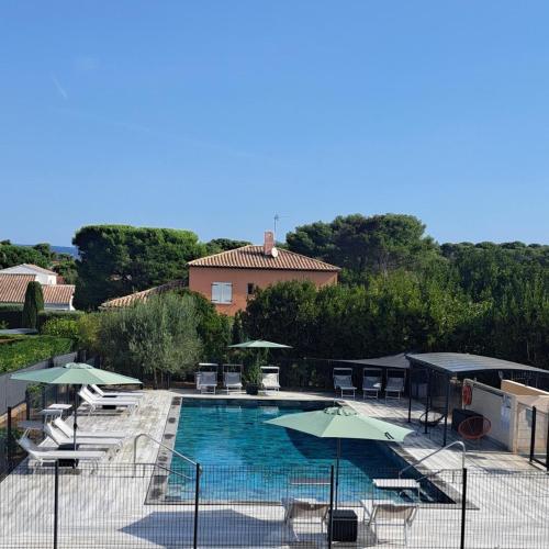 une piscine avec des chaises et des parasols et un bâtiment dans l'établissement Gîte Villa de 78 m2 à 400m de la plage + piscine, à Six-Fours-les-Plages